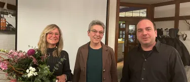 3 Personen vor Plakatwand